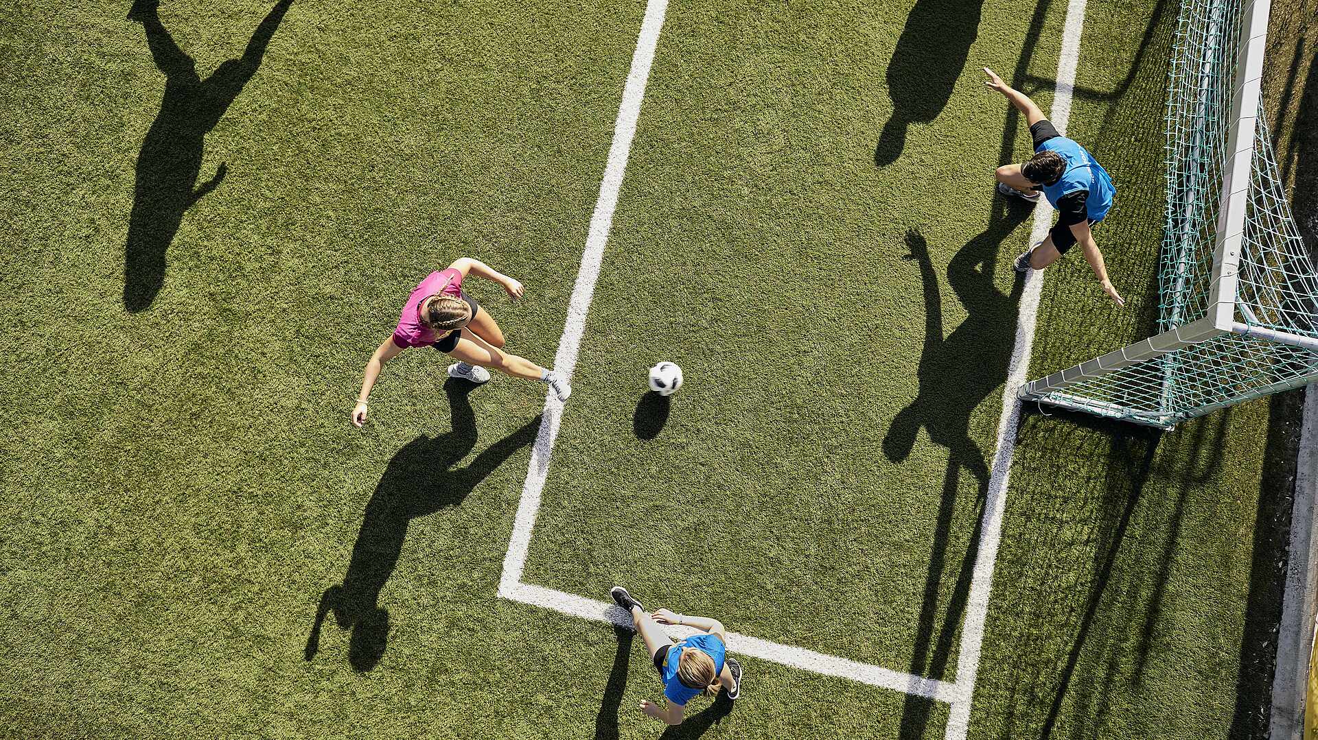 Drei Gäste spielen Fußball – gesehen aus der Vogelperspektive.
